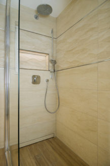 Ebenerdige Dusche mit Natursteinhighlights an der Wand